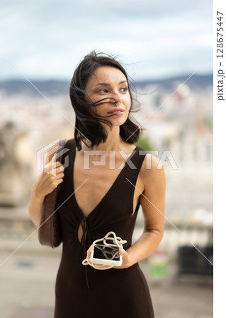 Woman walks through historical center of Barcelona with phone 128675447