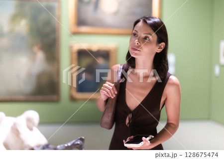 Woman with phone in hands in museum hall, view statues exhibition. 128675474