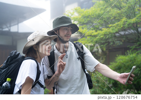 霧の中で旅館をバックに自撮り写真を撮るインバウンドの観光客 霧の中で旅館をバックに自撮り写真を撮るインバウンドの観光客 128676754