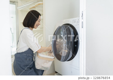 洗濯機に洗濯物を入れる50代の女性 128676854