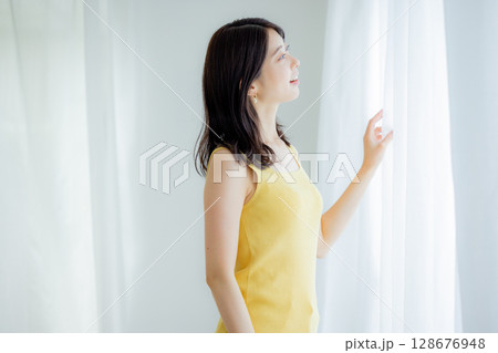 カーテンを開ける女性 128676948