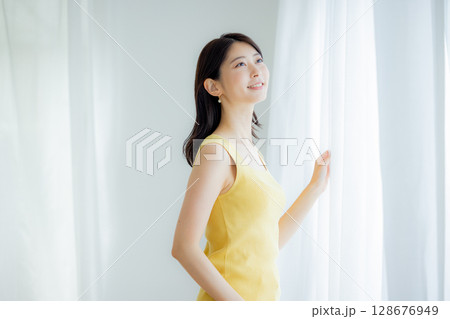 カーテンを開ける女性 128676949