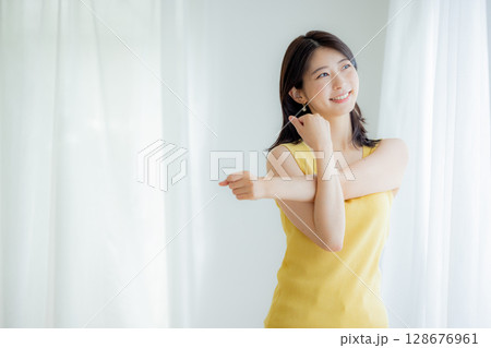 カーテンから日差しを浴びる女性 128676961