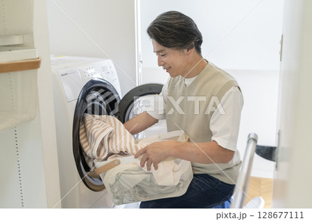 洗濯機に洗濯物を入れる50代の男性 128677111