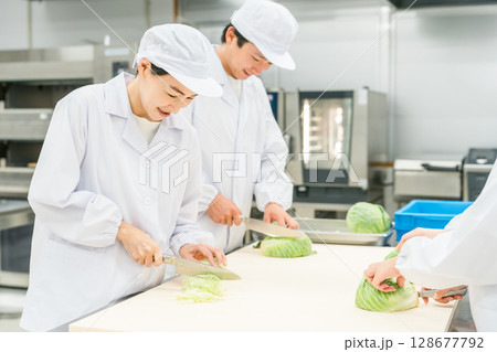 キッチン,バックヤードでキャベツを切る調理スタッフの男女 128677792