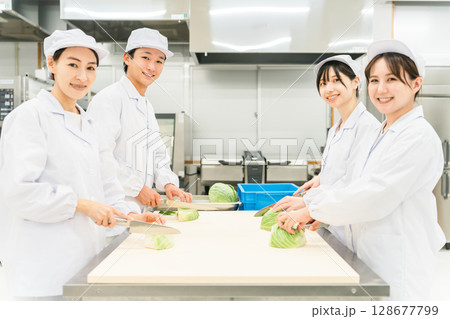 キッチン,バックヤードでキャベツを切る調理スタッフの男女 128677799