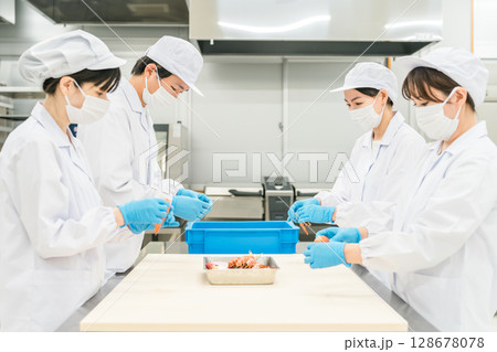 食材の下準備,仕込みをする衛生服姿の男女スタッフ 128678078