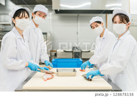 魚を調理するコックコート姿の男女スタッフ(調理師・料理人・生鮮市場・食品加工) 魚を調理するコックコート姿の男女スタッフ(調理師・料理人・生鮮市場・食品加工) 128678138