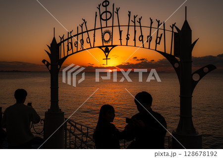 沖縄の沈む夕陽とカップルのシルエット 128678192