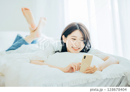 ベッドでスマホを見る女性 128678404