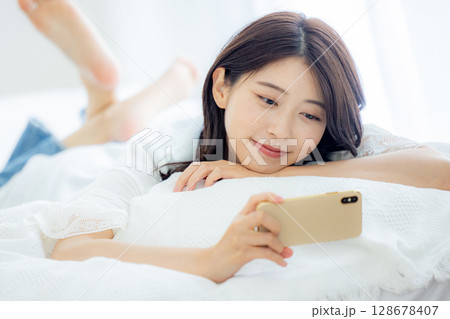 ベッドでスマホを見る女性 128678407