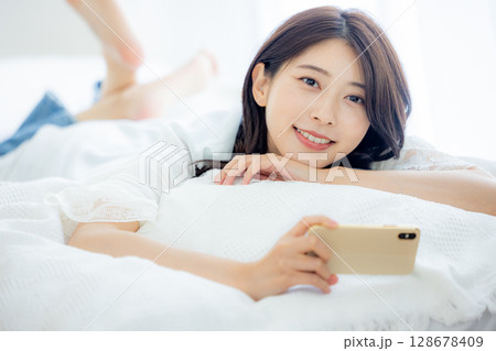 ベッドでスマホを見る女性 ベッドでスマホを見る女性 128678409