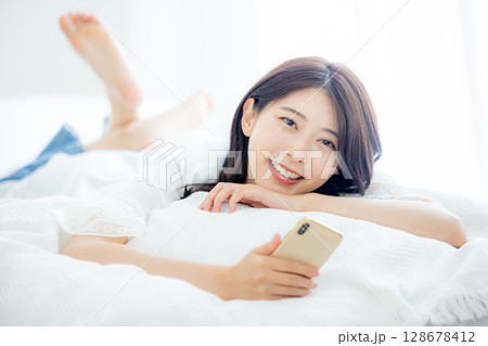 ベッドでスマホを見る女性 ベッドでスマホを見る女性 128678412