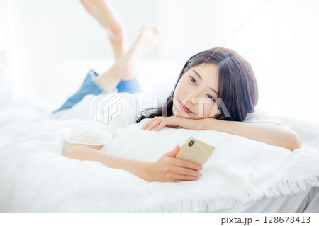 ベッドでスマホを見る女性 ベッドでスマホを見る女性 128678413