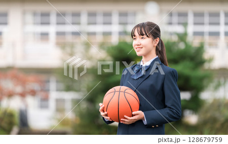 バスケットボールを持って校庭に立つ制服姿の高校生,中学生,小学生の女の子 128679759