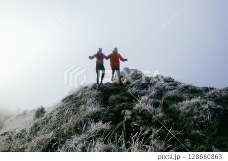 Trail running couple man and woman running on a mountain path 128680863