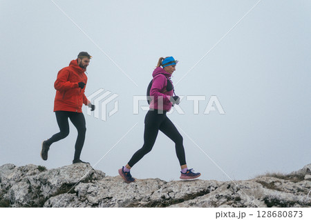 Trail running couple man and woman running on a mountain path Trail running couple man and woman running on a mountain path 128680873