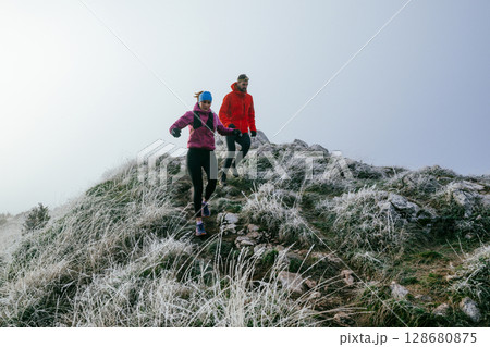 Trail running couple man and woman running on a mountain path Trail running couple man and woman running on a mountain path 128680875