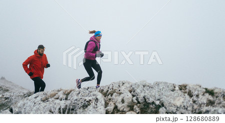 Trail running couple man and woman running on a mountain path Trail running couple man and woman running on a mountain path 128680889
