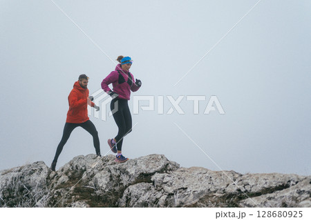 Trail running couple man and woman running on a mountain path Trail running couple man and woman running on a mountain path 128680925
