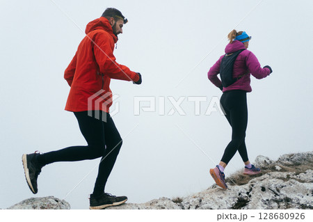Trail running couple man and woman running on a mountain path Trail running couple man and woman running on a mountain path 128680926