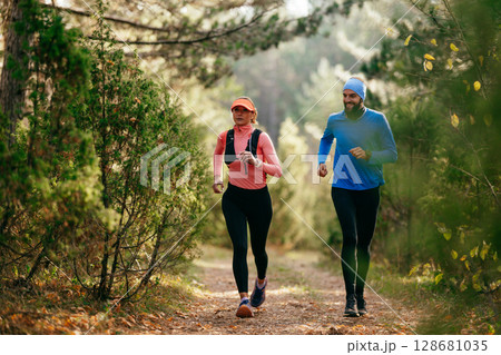 Happy Couple Running on a Forest Trail Happy Couple Running on a Forest Trail 128681035