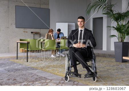 A businessman in a wheelchair navigating through a busy office, surrounded by his colleagues who are actively engaged in their work and collaboration A businessman in a wheelchair navigating through a busy office, surrounded by his colleagues who are actively engaged in their work and collaboration 128681067