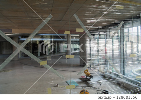 A captivating view of a modern business building under construction, showcasing its raw industrial interior with exposed steel beams and concrete walls bathed in the warm, golden hues of a sunset 128681356