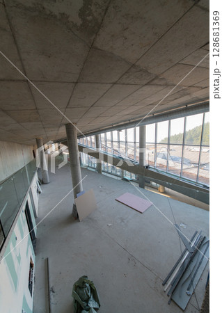 A captivating view of a modern business building under construction, showcasing its raw industrial interior with exposed steel beams and concrete walls bathed in the warm, golden hues of a sunset A captivating view of a modern business building under construction, showcasing its raw industrial interior with exposed steel beams and concrete walls bathed in the warm, golden hues of a sunset 128681369