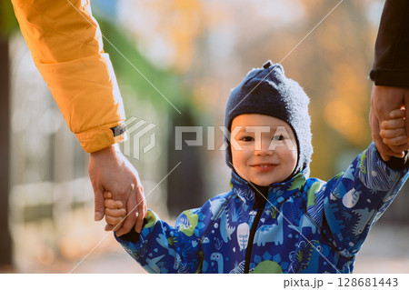 Parents walking hand in hand with their son through the charming city streets, enjoying the warmth of the season and creating joyful memories together 128681443