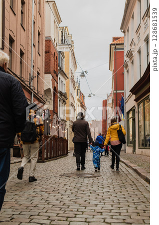 Parents walking hand in hand with their son through the charming city streets, enjoying the warmth of the season and creating joyful memories together 128681539