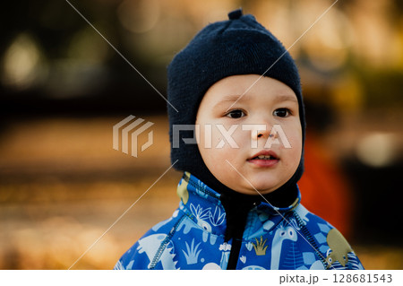 A joyful little boy in his winter coat and hat plays happily in the park, surrounded by the love and warmth of his smiling parents 128681543