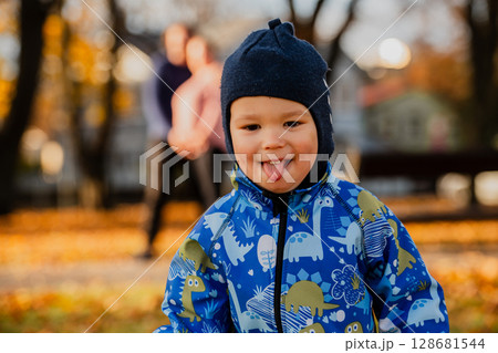 A joyful little boy in his winter coat and hat plays happily in the park, surrounded by the love and warmth of his smiling parents 128681544