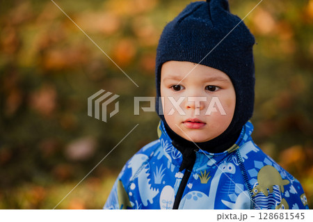 A joyful little boy in his winter coat and hat plays happily in the park, surrounded by the love and warmth of his smiling parents 128681545