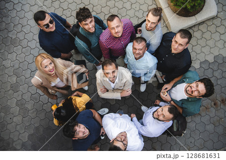 Top view photo of a group of business people and colleagues standing together holding hands, looking towards the camera, symbolizing unity and teamwork. Top view photo of a group of business people and colleagues standing together holding hands, looking towards the camera, symbolizing unity and teamwork. 128681631