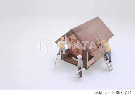 Miniature Workers Building and Constructing Large Wooden Models 128681714