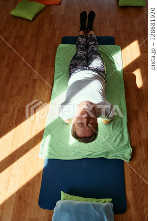 Senior woman practicing stretching and meditation on the floor, focusing on proper alignment and relaxation. Senior woman practicing stretching and meditation on the floor, focusing on proper alignment and relaxation. 128681920