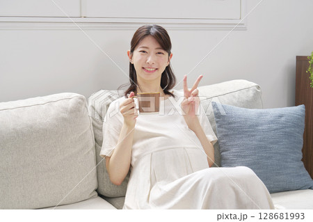 自宅でカフェインレスコーヒーを飲む妊婦　ピースサイン 128681993