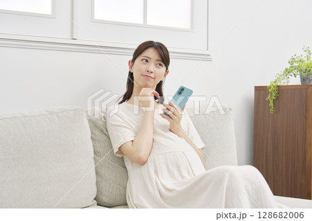 スマートフォンを持って考える妊婦　リビング 128682006