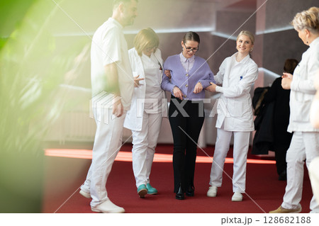 Medical team helping patient with walking therapy 128682188