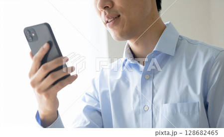 パステルシャツでスマホを持つ若手男性 128682465