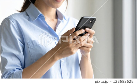 ロールアップ袖の日本人女性とスマートフォン 128682629