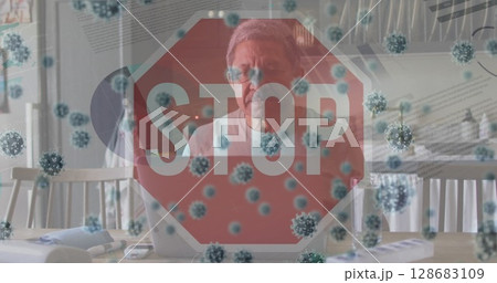 Working elderly man using laptop in dining area, with stop sign graphic and virus particles Working elderly man using laptop in dining area, with stop sign graphic and virus particles 128683109