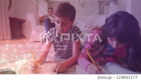 Image of sparkles over diverse pupils writing in notebooks 128683177