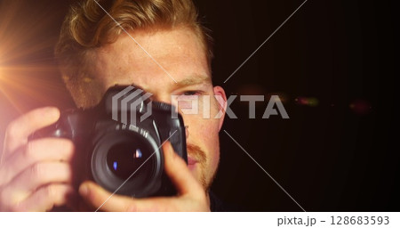 Image of light over caucasian male photographer with camera on black background Image of light over caucasian male photographer with camera on black background 128683593