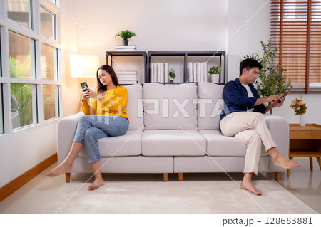 Unhappy asian couple sitting on sofa having relationship problem in living room at home. 128683881