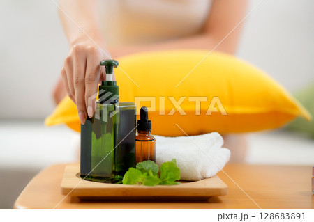 Closeup hands young asian woman cheerful holding skincare or cream sitting on sofa at home. 128683891