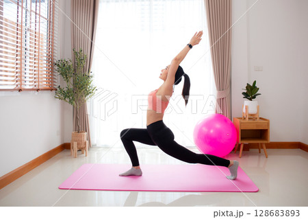 Young asian woman in activewear yoga pose on mat with meditation in living room at home. Young asian woman in activewear yoga pose on mat with meditation in living room at home. 128683893
