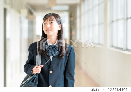 学校の廊下を歩く制服姿の小学生,中学生,高校生の女子生徒 128684101