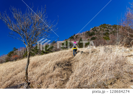 冬の扇平の草原を行くハイカーと乾徳山山頂 冬の扇平の草原を行くハイカーと乾徳山山頂 128684274